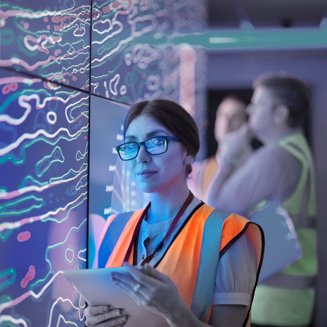 Image of a woman wearing a reflective vest, holding papers 