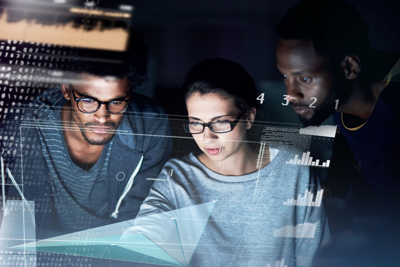 Shot of a group of programmers working on a computer code at night